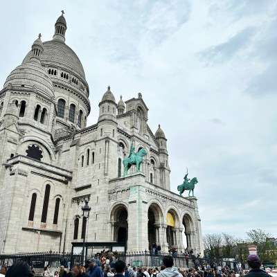 Sacré-Cœur on a Paris Spring Day — Seen from the side, the basilica rises above the lively crowds of Montmartre beneath a typically changeable Paris sky.
