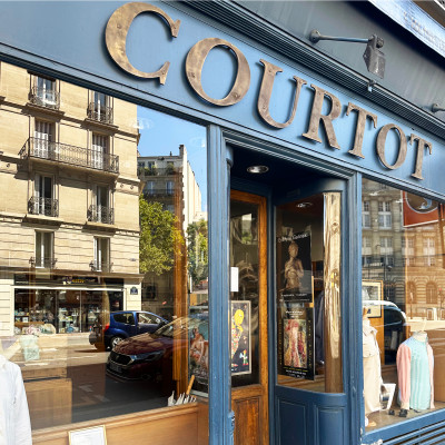 Maison Courtot – A timeless Parisian atelier specializing in bespoke shirtmaking. This image captures the intricate craftsmanship of a master shirtmaker at work, expertly tailoring fabric to create a personalized, perfectly fitted shirt. The artistry and precision reflect Maison Courtot’s commitment to the highest standards of quality and luxury in shirtmaking.
