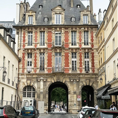 One of the historic entrances to Place des Vosges, where a grand red-brick pavilion opens into a hidden square that has welcomed Parisians and visitors for centuries.
