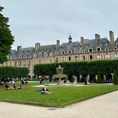 Locals and visitors gather on the lawns of Place des Vosges, making it one of the most beloved places in the Marais for a quiet pause beneath the historic arcades.
