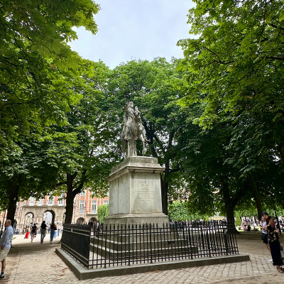 At the heart of Place des Vosges stands the equestrian statue of Louis XIII, framed by mature chestnut trees and the timeless symmetry of the square.
