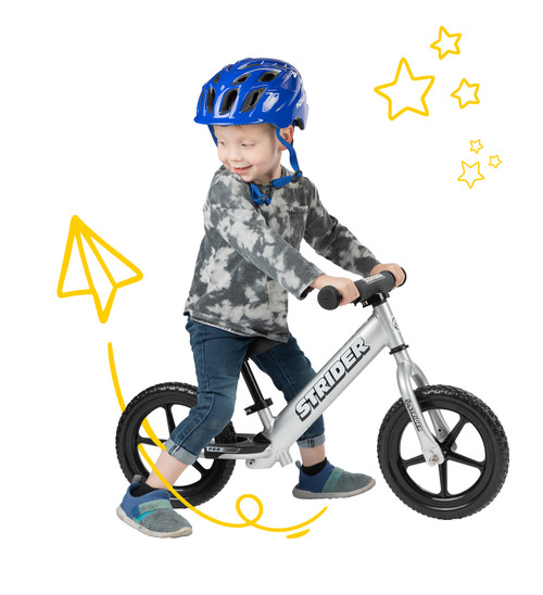 Young child on a silver 12 Pro balance bike in a studio with yellow digital doodles surrounding them