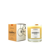 This a candle labeled "CHAKRA 2 SOY CANDLE" by AD KILIBREW. It's an orange soy candle in a clear glass container, designed for chakra balancing and aromatherapy.