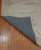 Corner of the rug is flipped up showing texture on the bottom. Corner of the rug is flipped up showing texture on the bottom.