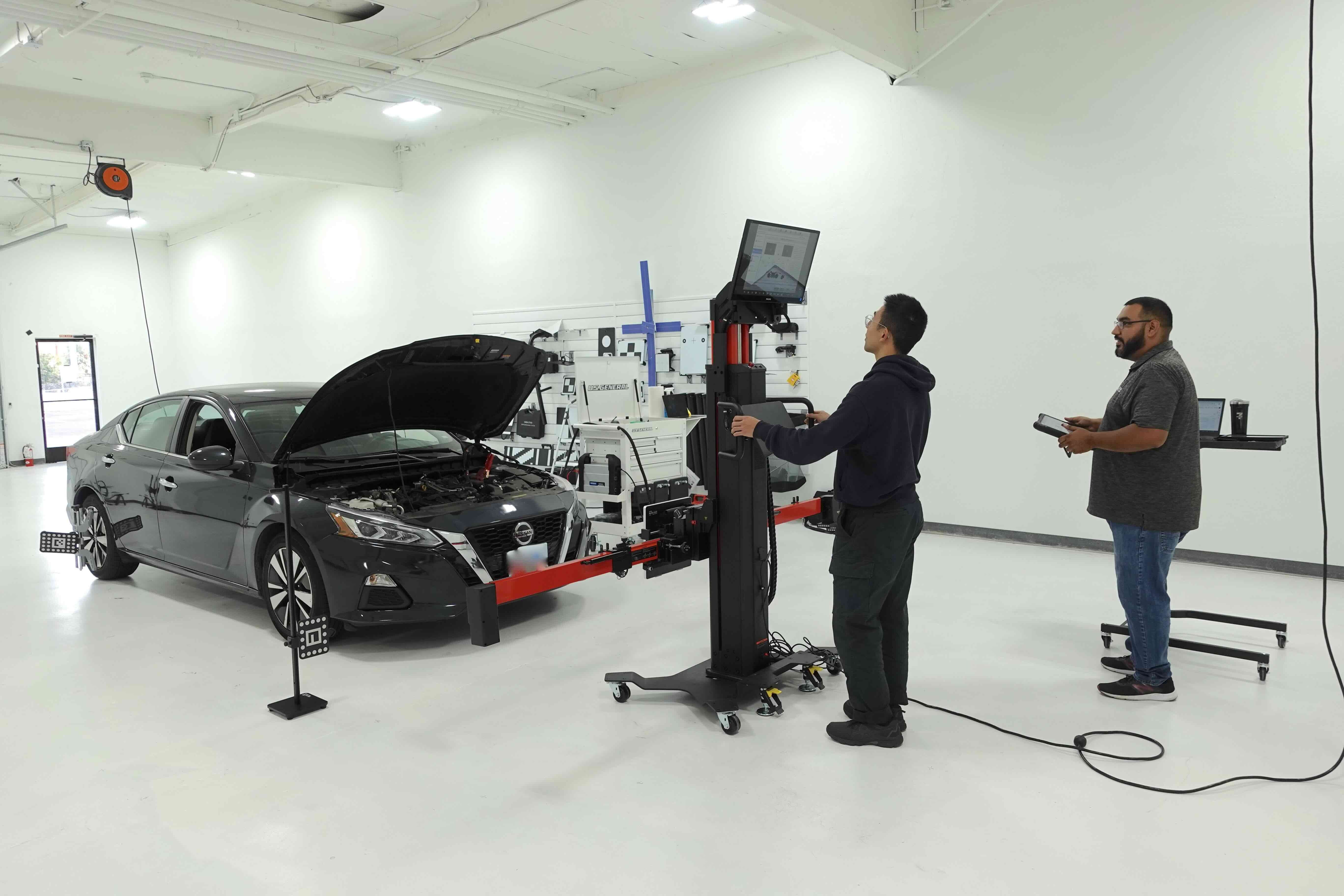 Showroom and calibration facility with a person manning a calibration frame, calibrating a car