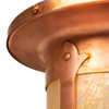 Rivet and design details on a Spanish Colonial Revival post mounted light fixture with a raw copper finish and warm, golden glass. 