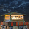 A classic, traditional sloped-roof column mounted pier light fixture with crown molding accent, an aged patina finish and iridescent glass. In the background is a dramatic, cloudy sunset. 