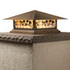 A classic, traditional sloped-roof column mounted pier light fixture with crown molding accent, an aged bronze finish, floral artwork and golden glass. 