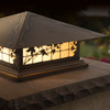 A classic, traditional sloped-roof column mounted pier light fixture with crown molding accent, an aged bronze finish, floral artwork and golden glass. 