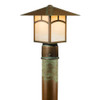 A linear, formal Craftsman lantern with an aging patina finish and warm glass on a brass post. This Arts & Crafts fixture has window pattern artwork on the body.