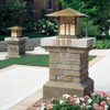 A pair of linear, formal Craftsman pier lanterns with an aging patina finish and warm glass installed on brick columns in a driveway. This Arts & Crafts fixture has an Asian cloud lift pattern artwork on the body. 
