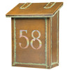 A classic, solid brass, vertical mailbox with an aged patina finish and glass-backed house address numbers. 