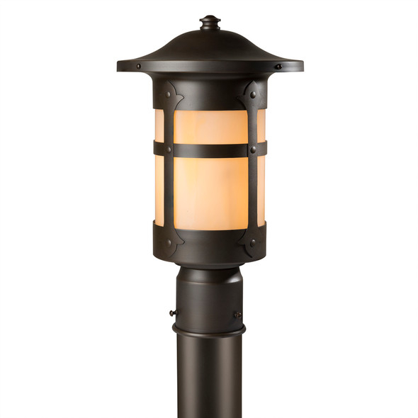 A Spanish Colonial Revival post mounted light fixture with a bronze finish and warm, golden glass.