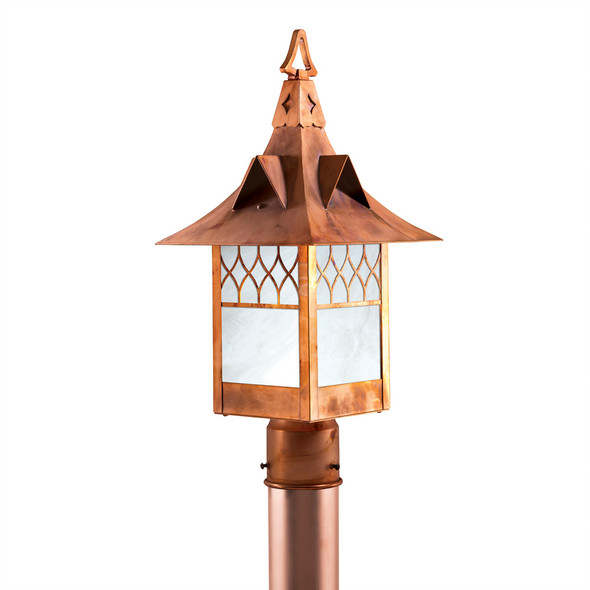 A Victorian, Gothic Revival style post mounted light fixture with a church window pattern, raw copper finish and white glass.