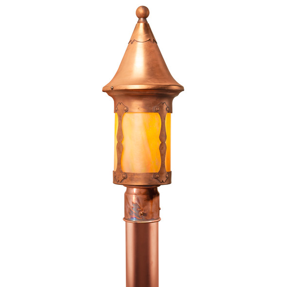 A Victorian, storybook lantern mounted on a brass post with an aging, raw copper finish and golden glass.