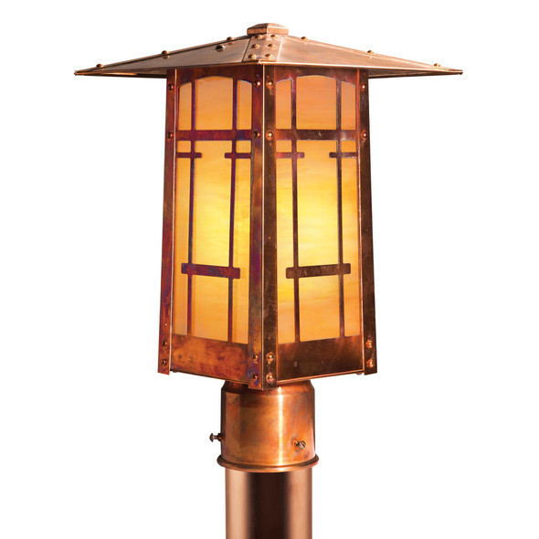 A vertical, linear Arts & Crafts post mounted light fixture with horizontal metal accents with a raw copper finish and glowing, iridescent glass.