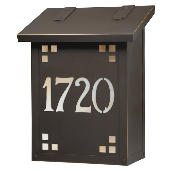 A vertical brass mailbox with a bronze finish, glass corner accents and address numbers on the front backed by glass. 