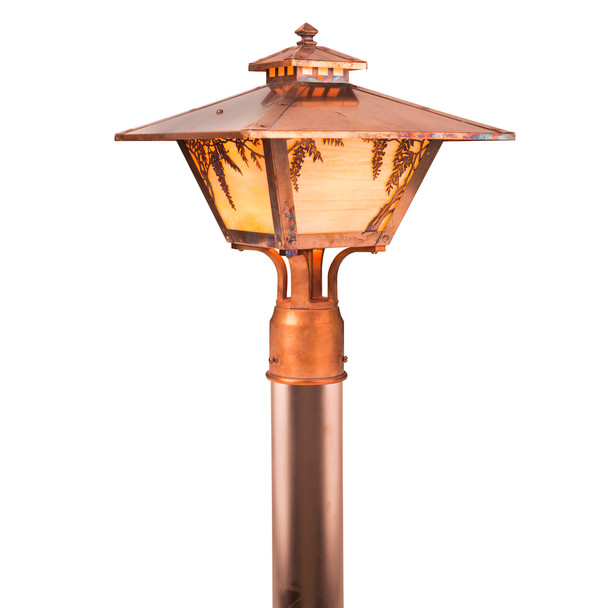 An Arts & Crafts style post mounted landscaping light fixture with a cupola, a dramatic taper, a raw copper finish and warm glass. The Craftsman fixture has wisteria artwork.