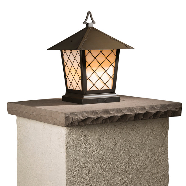 A classic, traditional sloped-roof column mounted pier light fixture with crown molding accent, a bronze finish and warm white glass. 