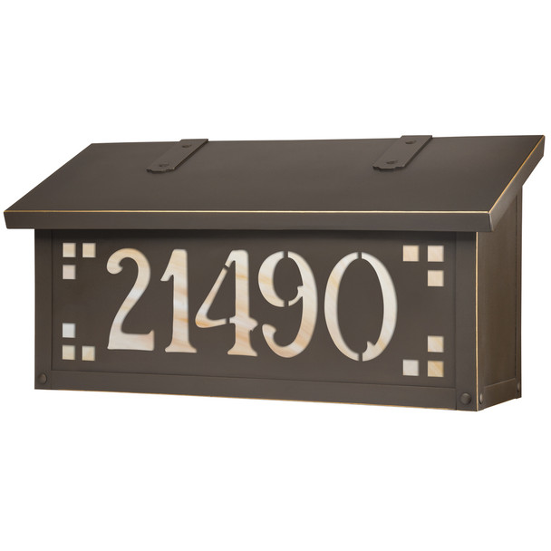 A horizontal brass mailbox with a bronze finish, glass corner accents and address numbers on the front backed by glass. 