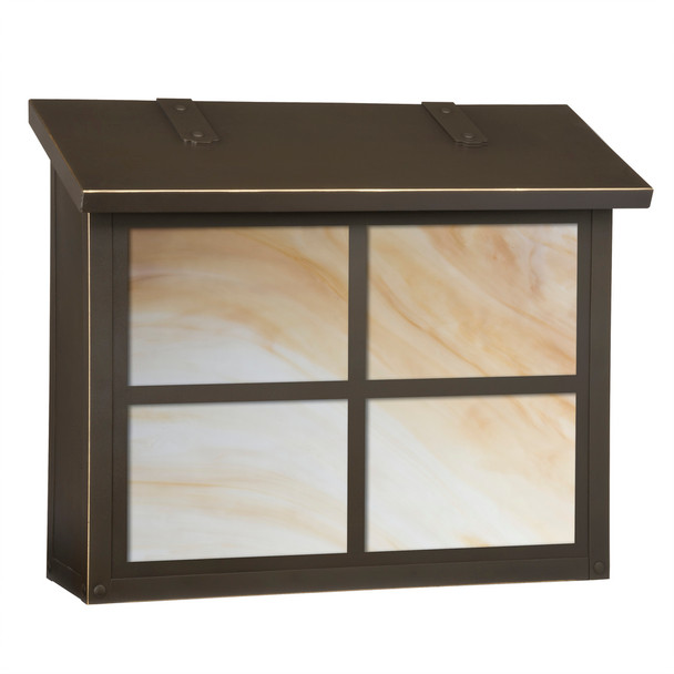 A large brass mailbox with a bronze finish, warm glass and a cross design on the front panel. 