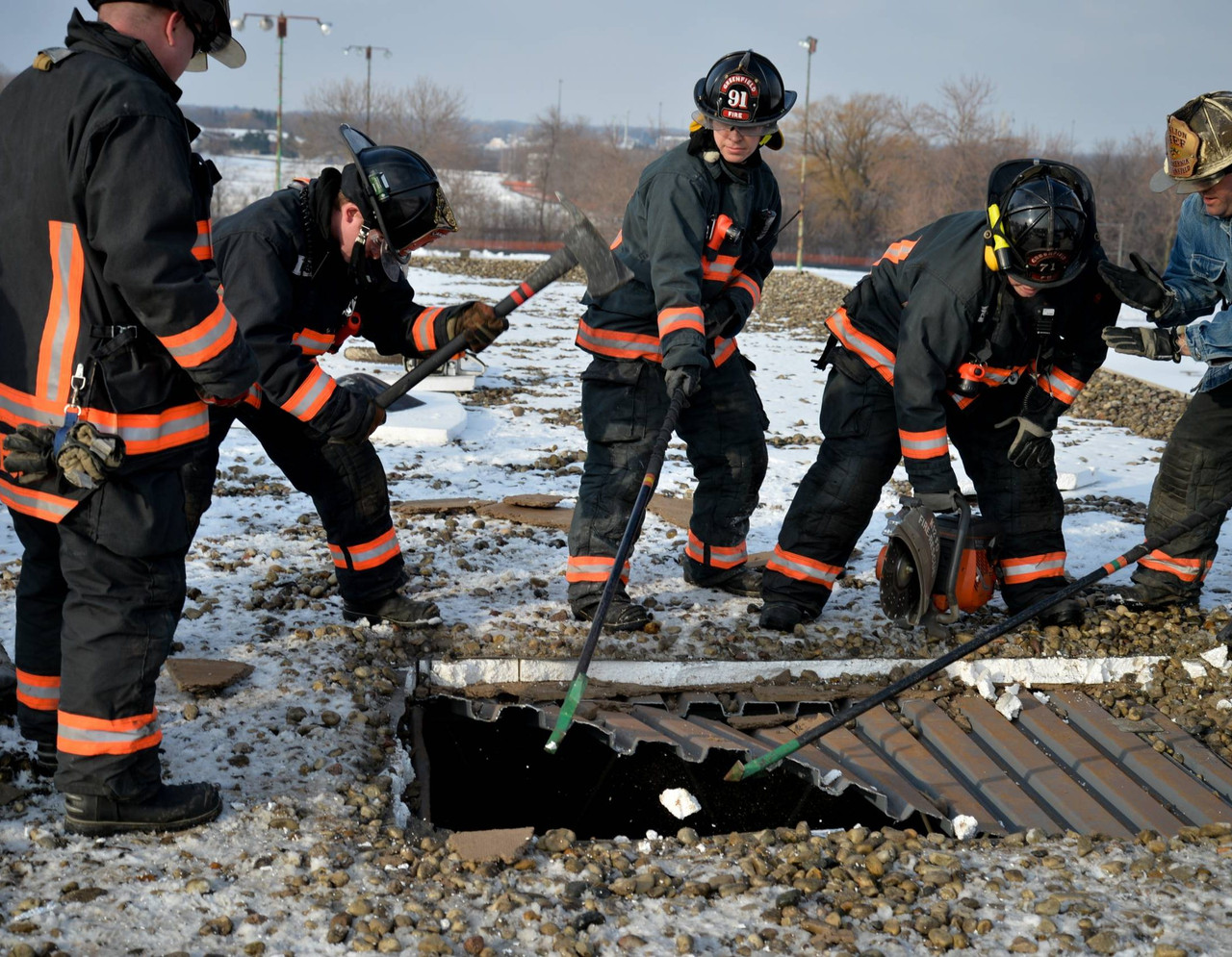 Firefighters opening a roof with hooks, a halligan and an axe
