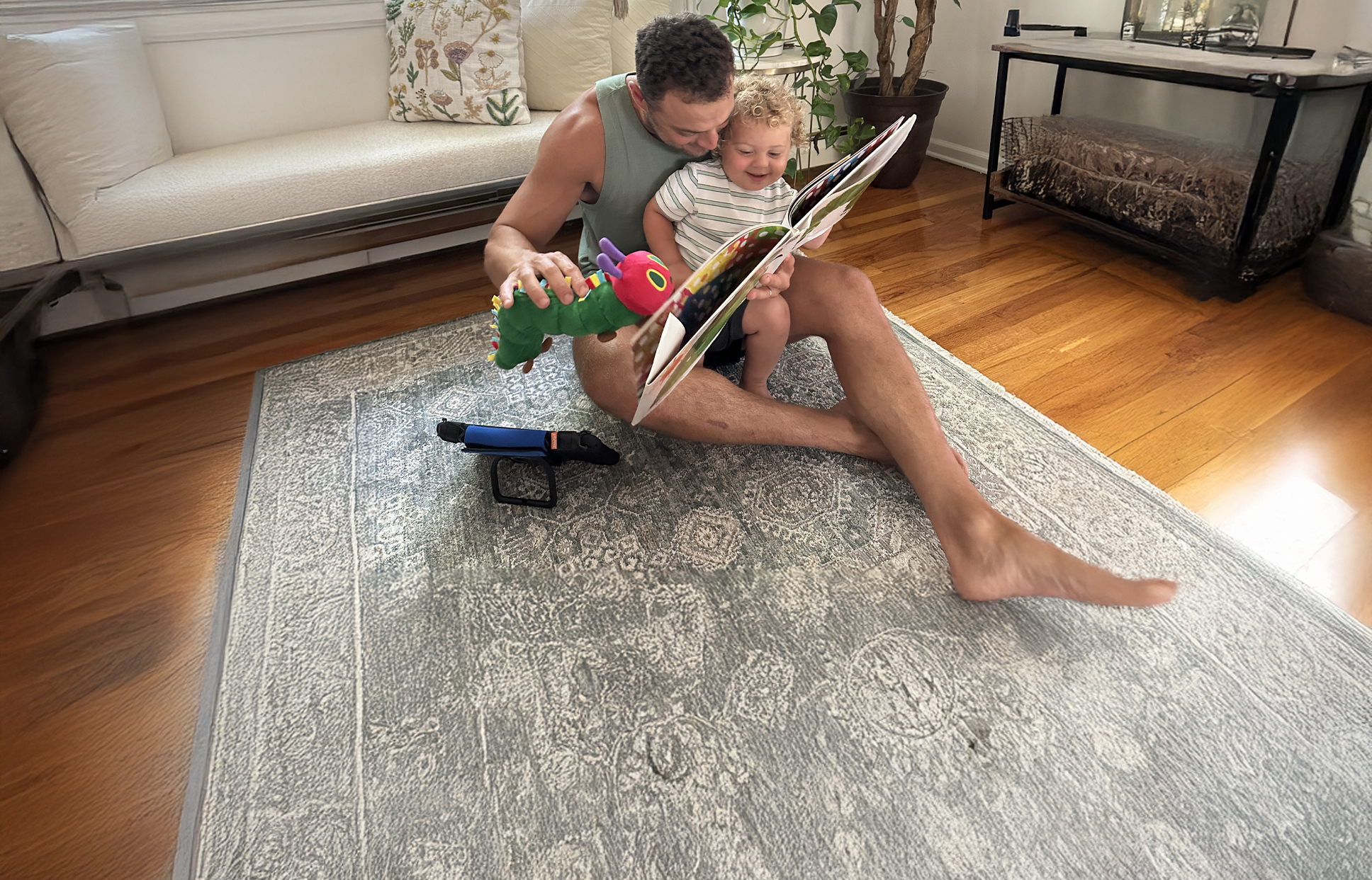 A dad sitting on the floor reading to his child.