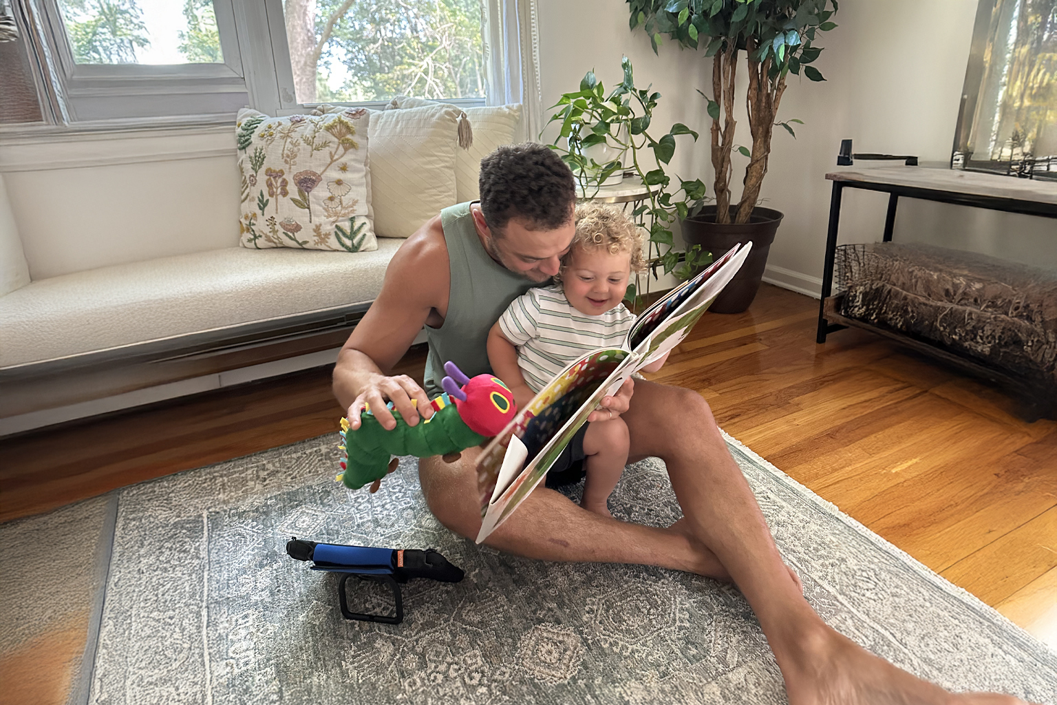 A dad sitting on the floor reading to his child.