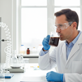 Scientist in a lab coat drinking coffee from a glass beaker-style mug in a modern laboratory