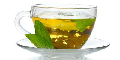 a glass of tea with a leaf on top