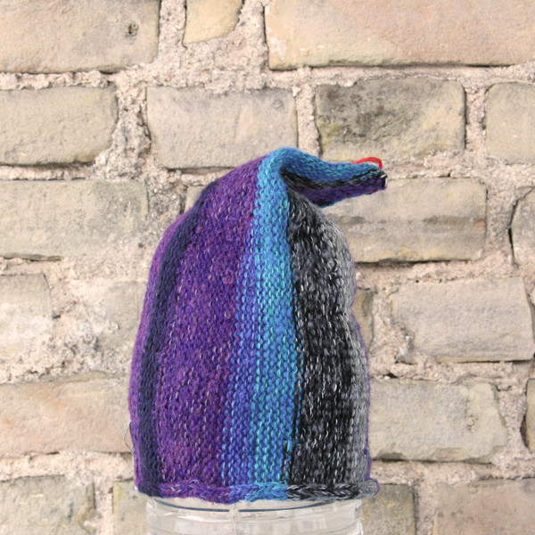 City Night S/M pixie gnome hat knit by Wrapture by Inese in front of brick wall