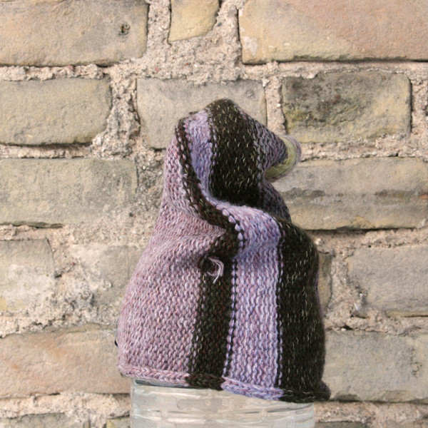 Raisin S/M pixie gnome hat knit by Wrapture by Inese in front of brick wall