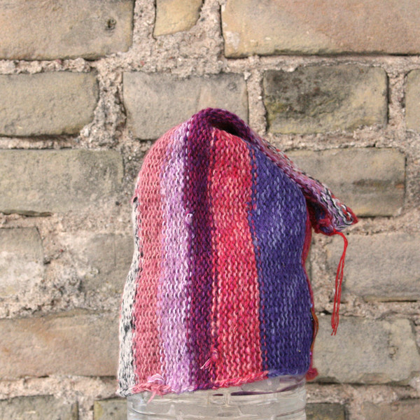 Pink S/M pixie gnome hat knit by Wrapture by Inese in front of brick wall