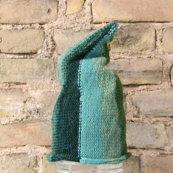 Willow S/M pixie gnome hat knit by Wrapture by Inese in front of brick wall