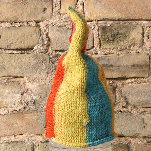 Yellow Stripe  S/M pixie gnome hat knit by Wrapture by Inese in front of brick wall