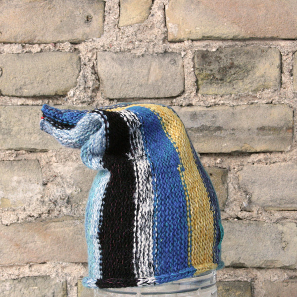 Blue Skies S/M pixie gnome hat knit by Wrapture by Inese in front of brick wall
