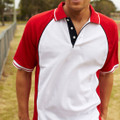 Man wearing white pique knit polo with red raglan sleeves, navy placket, and white tipping on collar and cuffs