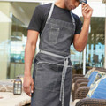 Charcoal denim waist apron with contrast stitching, chest pocket, and grey ties over dark t-shirt