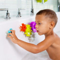 Young child playing with colourful interlocking gear bath toys stuck to white bathtub wall