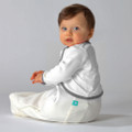 Baby wearing cream long-sleeve arm warmers with grey contrast trim and teal brand tab, seated against light grey background