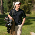 Black short sleeve polo shirt with contrasting stone collar, worn by man on golf course