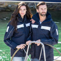Man and woman on sailboat wearing navy wind and waterproof jackets with white chest panels and reflective piping