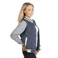 Woman wearing navy marle and grey varsity jacket with white rib collar, cuffs, and contrast snap-button front