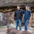 Man and woman wearing midnight navy 3-layer shell jackets with hood, zip pockets, and panelled construction on rocky terrain