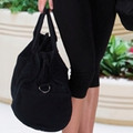 Black canvas oxford drawstring bag with ring detail, held by model against outdoor background