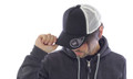 Navy front panel trucker cap with white mesh back and curved brim worn by model in charcoal hoodie