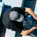 Overhead view of man wearing charcoal heather snapback cap with flat brim and woven side label