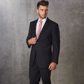 Black stretch corporate jacket with notch lapels and two-button closure, worn with white shirt and pink tie