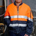 Man wearing orange and navy hi-vis flying jacket with silver 3M reflective tape bands and front zip