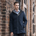 Man wearing navy lightly padded jacket with snap-button placket, contrast hood lining, and side pockets against brick wall